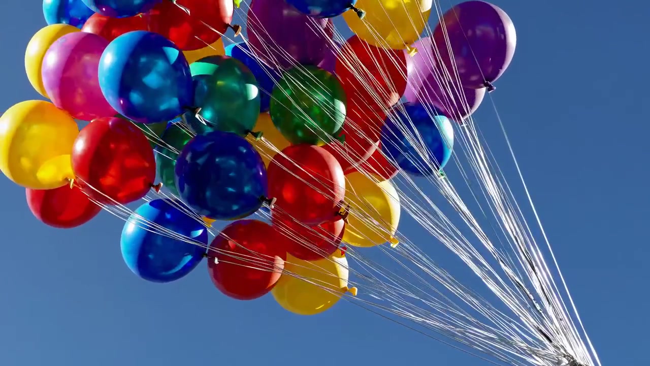 Farverige balloner svævende mod en klar blå himmel