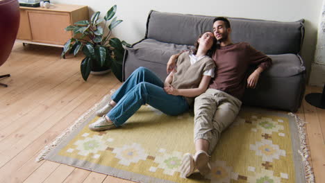 una pareja joven sentada en la alfombra.