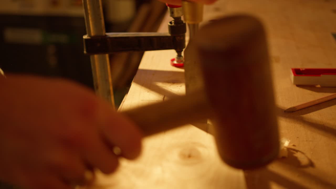 Primo piano di un uomo che martella nel suo laboratorio, intagliando su una tavola di legno