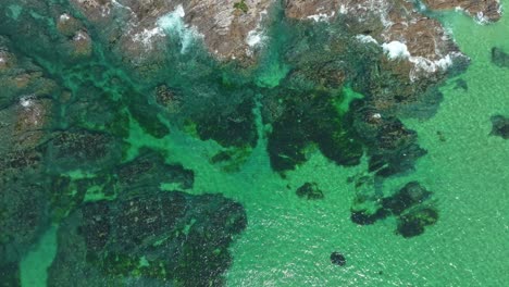 cornish coastal rocks at constantine bay with an aerial top down view over water, dolly forward, cornwall, uk