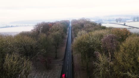 Reveal-drone-footage-of-treelined-approach-to-Castle-Howard-on-winter-day-with-snow-in-the-fields-dropping-low-at-the-end