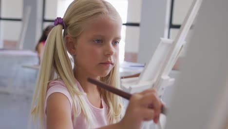 video of focused caucasian girl painting during art lessons at school