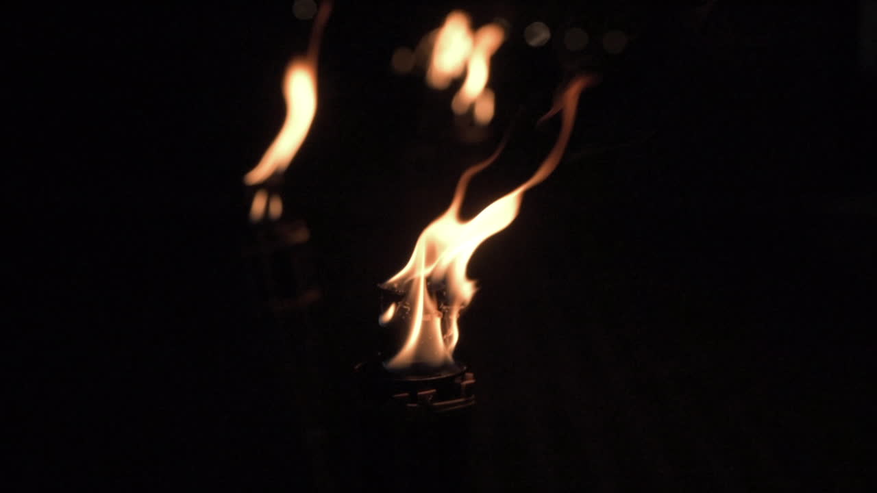 Scene with torches lit at night. Static, shallow focus