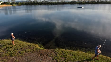 person fishing by a calm lake at sunset