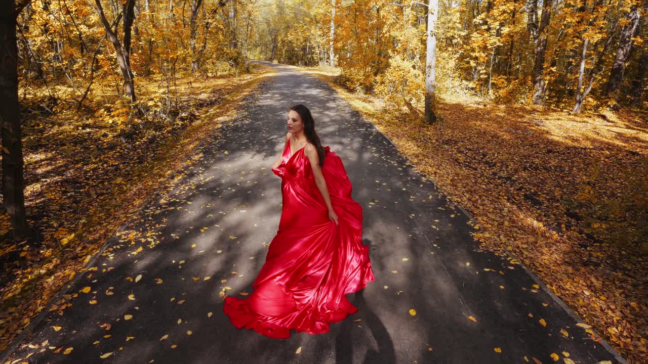 A Woman in a Flowing Red Dress Strolls Along a Scenic Autumn Path, Surrounded by Vibrant Fall Foliage and Soft, Golden Light Filtering Through the Trees