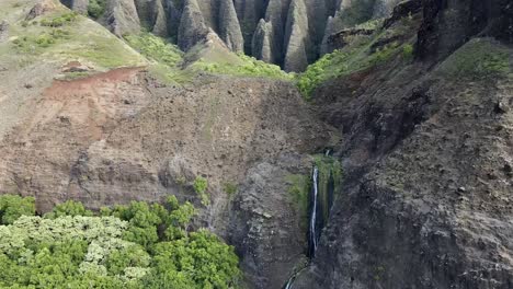 beautiful-serene-hawaii-waterfall-at-kalalau-beach-in-napali-state-park-kauai-hawaii-midday-dramatic-mountain-to-beach-landscape-lush-green-tropical-pan-up-with-waterfall-and-steep-cliffs