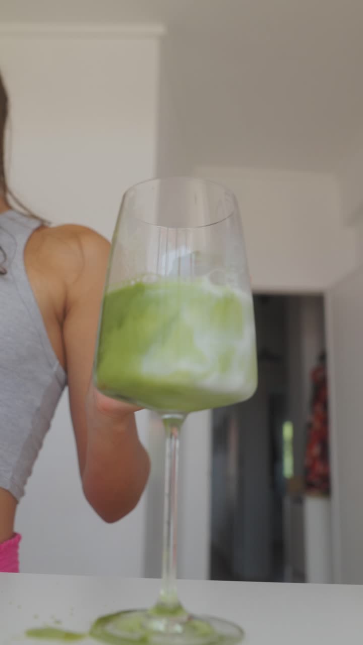 Pouring a green matcha drink into a glass
