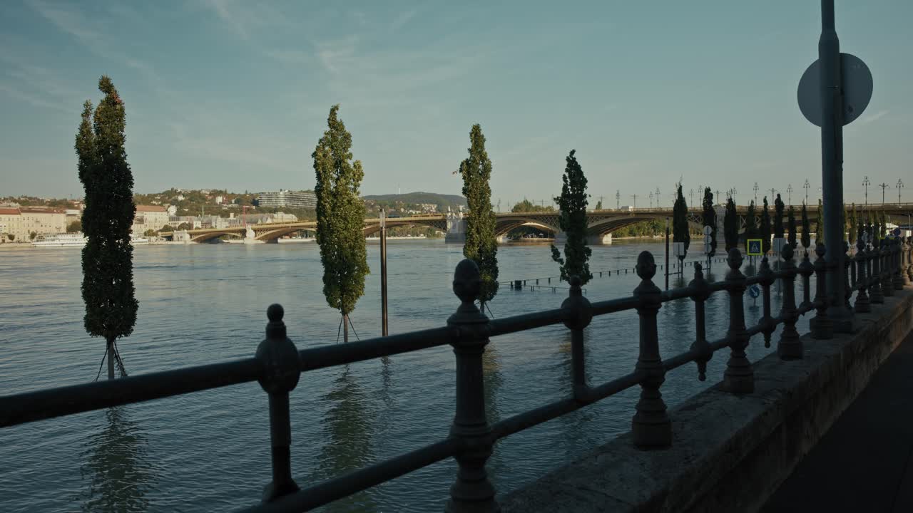 riverside view with submerged walkway, trees, and distant bridge, Budapest, Hungary