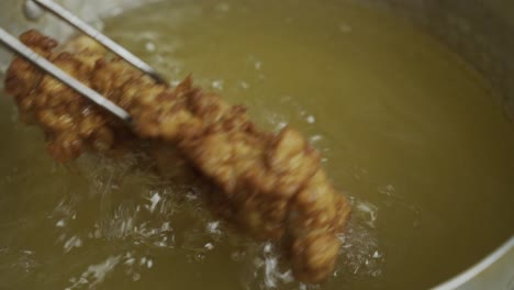 freír carne de pollo en aceite hirviendo caliente dentro de una sartén de metal