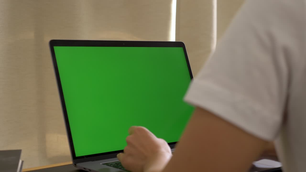 sobre el hombro de una mujer de negocios india que trabaja en el interior de la oficina en la pc en el escritorio, mirando la pantalla verde. persona de la oficina usando una computadora portátil con pantalla verde portátil, sentada en una mesa de madera