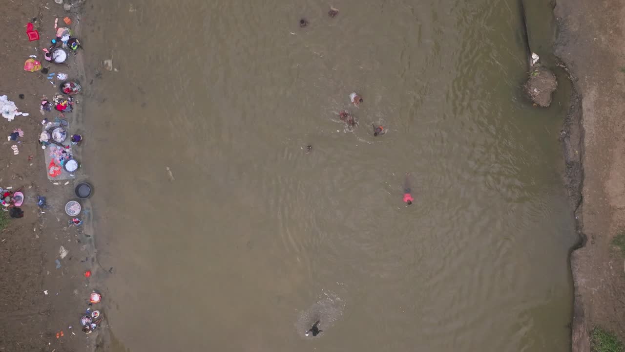 toma aérea de arriba hacia abajo de la población haitiana lavando ropa en el río en la frontera de república dominicana con haití