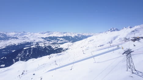 Aerial-panoramic-footage-of-ski-slopes-in-winter-mountain-resort.-Snow-capped-mountain-ridge-in-Alps.-Laax,-Switzerland