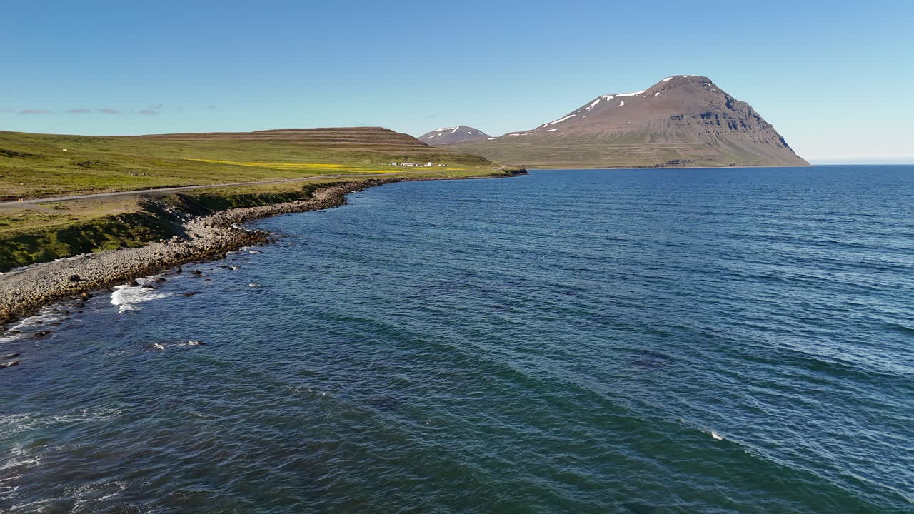 Bright aerial view of Greenland Sea shoreline in Austurland, showing blue ocean, cliffs, and open sky under sunny Icelandic conditions