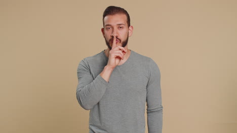 young lebanese man presses finger to lips makes silence gesture sign do not tells secret stop gossip