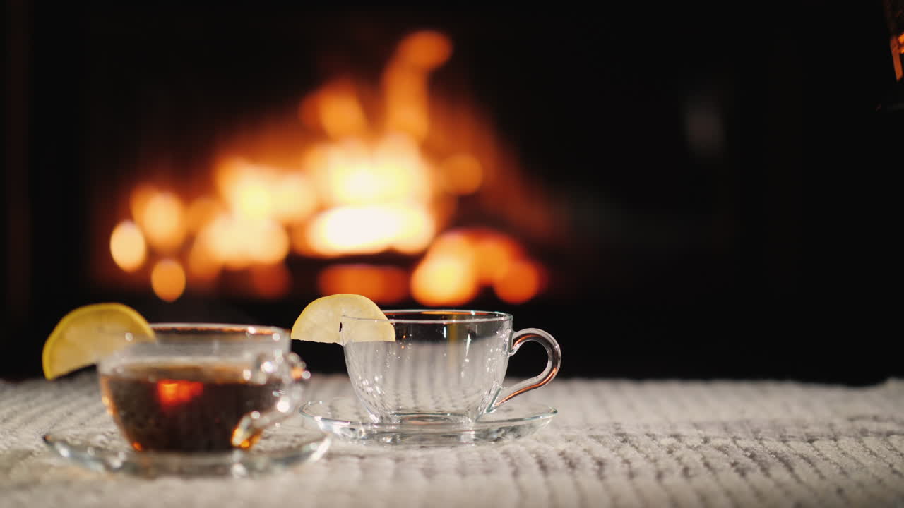아늑한 환경에서 벽난로 차를 배경으로 차를 컵에 붓습니다.