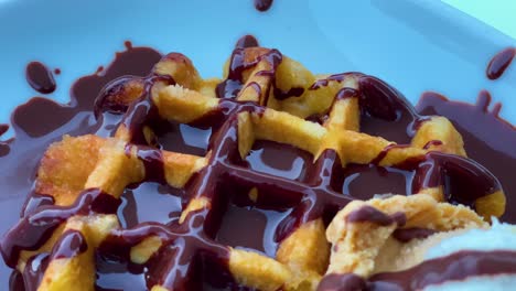 primer plano de un delicioso desayuno con gofres veganos sobre los que se vierte chocolate vegano o vegetariano sobre fondo negro