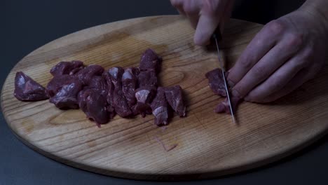 hombre cortando carne de res fresca en una tabla de madera - de cerca