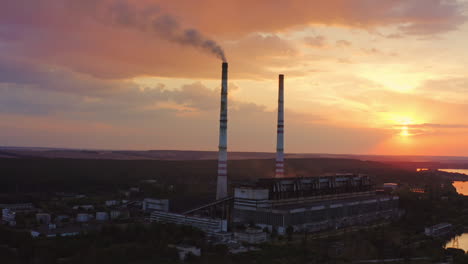 harmful factory in the countryside. industry with tower pipes on the evening sky with setting sun. chemical smoke from manufacture pollutes the air. view from above.