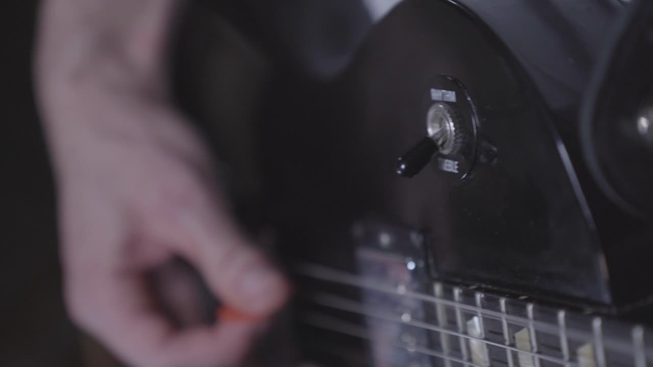 Close up of person playing electric guitar, flipping rhythm treble switch