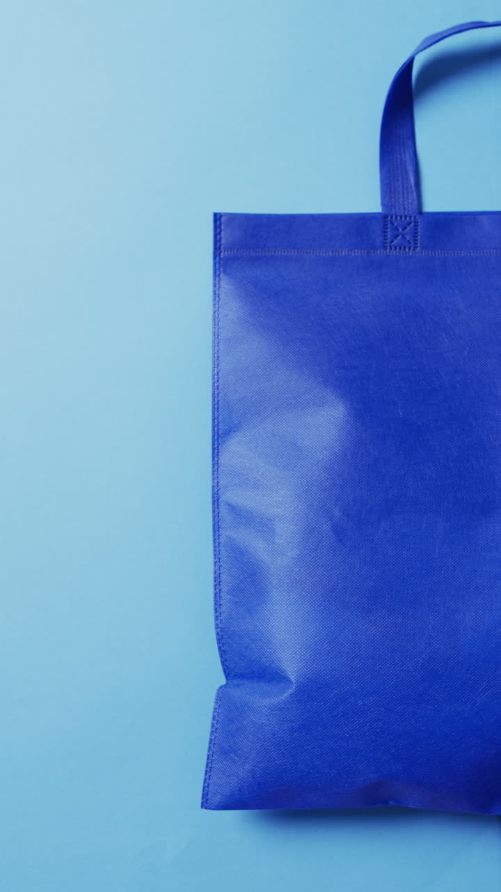 Vertical video of blue canvas bag with copy space on blue background