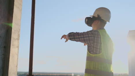 engineer the builder on the roof of the building stands in vr glasses and moves his hands using the interface of the future. futuristic engineer of the future.