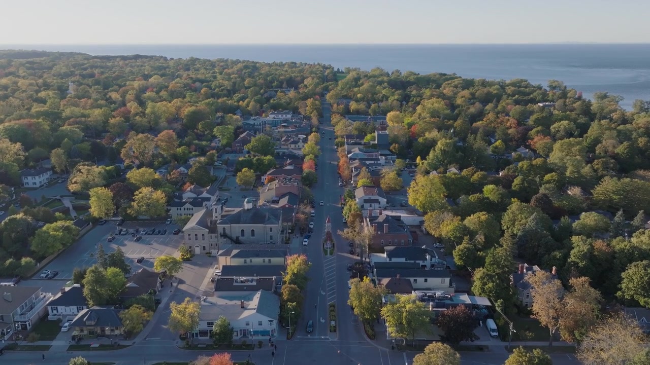 Niagara-on-the-Lake, Ontario'da, sonbaharda Queen Caddesi üzerinde uçan bir drone çekimi; tarihi ana cadde üzerindeki Anıt Saat Kulesi ve ötesindeki göl ile birlikte.