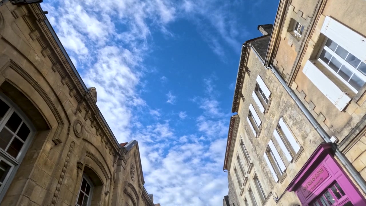 Ripresa in movimento dal basso di edifici storici in pietra calcarea contro cieli azzurri a Saint-Émilion, Francia