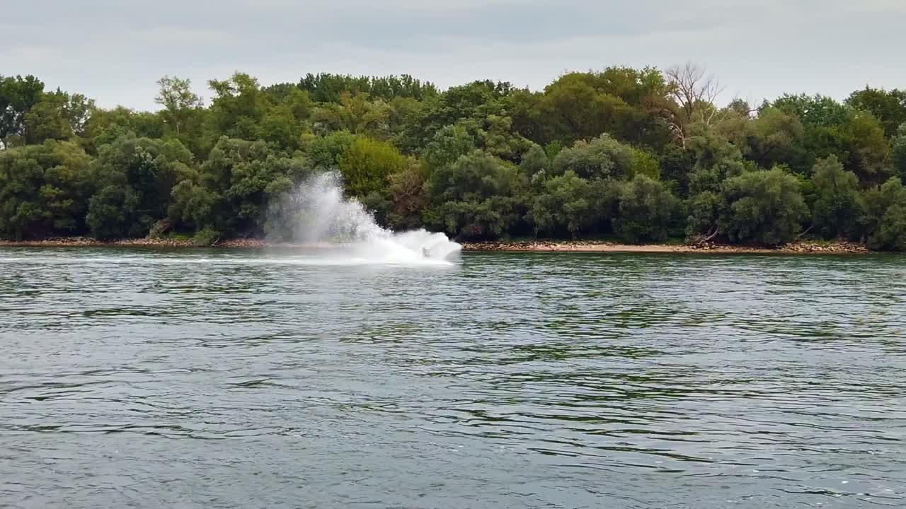 강, 슬로모 트래킹에서 재미있는 기동을 하는 동안 속도를 내는 제트 스키 뒤에서 물이 높이 스프레이됩니다.