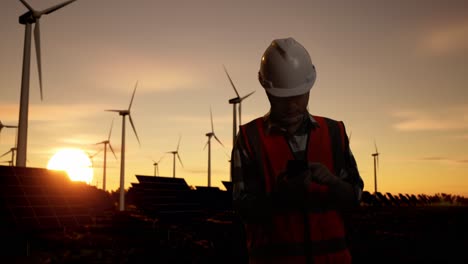 engineer working at a wind and solar farm at sunset