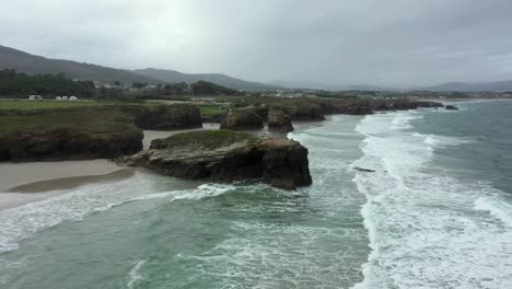 rocky landscape at wild coastal beach, aerial backward