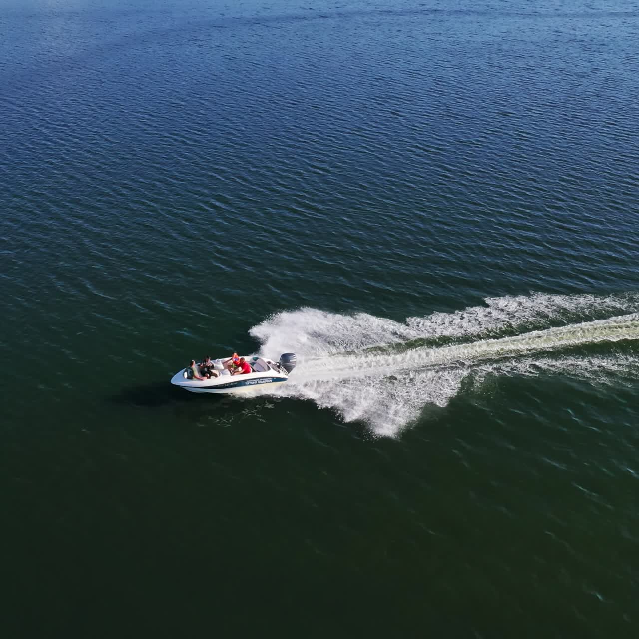 Motorboat on blue water surface. Tourists travel in a high-speed boat in the sea. White foam after the boat sailing on water. Aerial view.