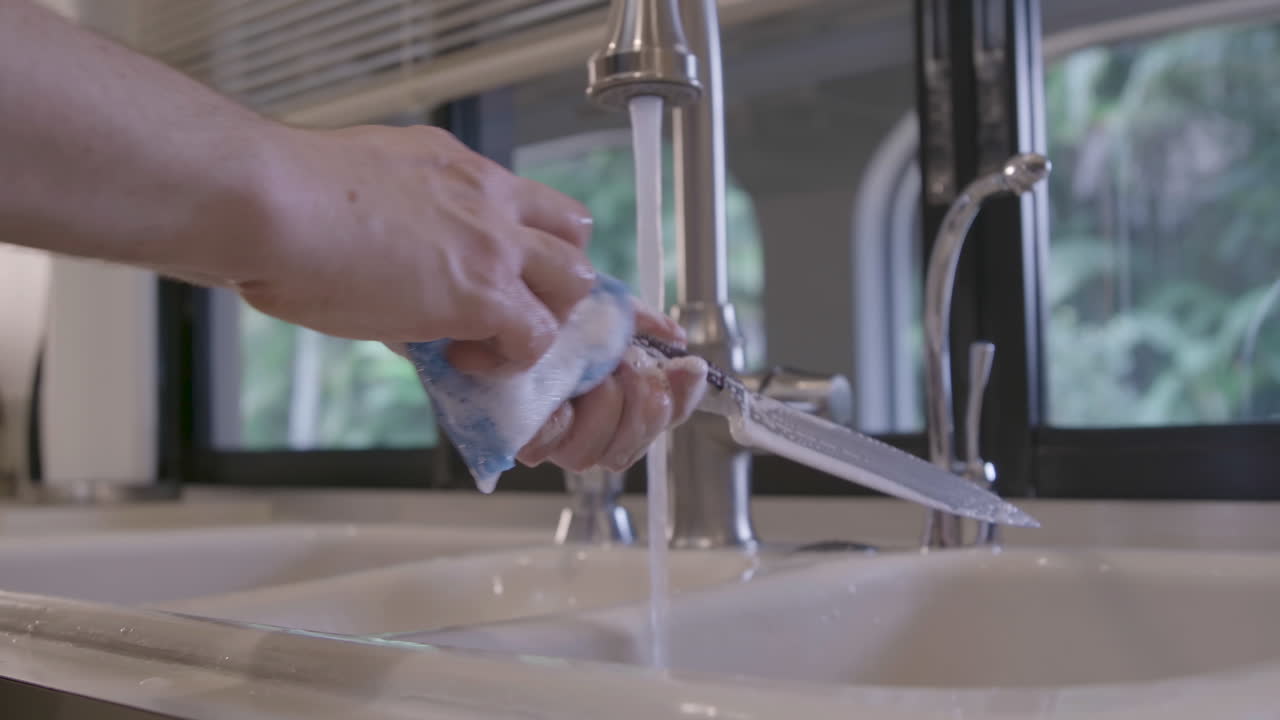 백인 남성이 집 부엌에서 칼을 닦고 있다