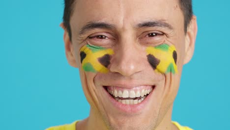 man with a jamaican flag painted on the face smiling
