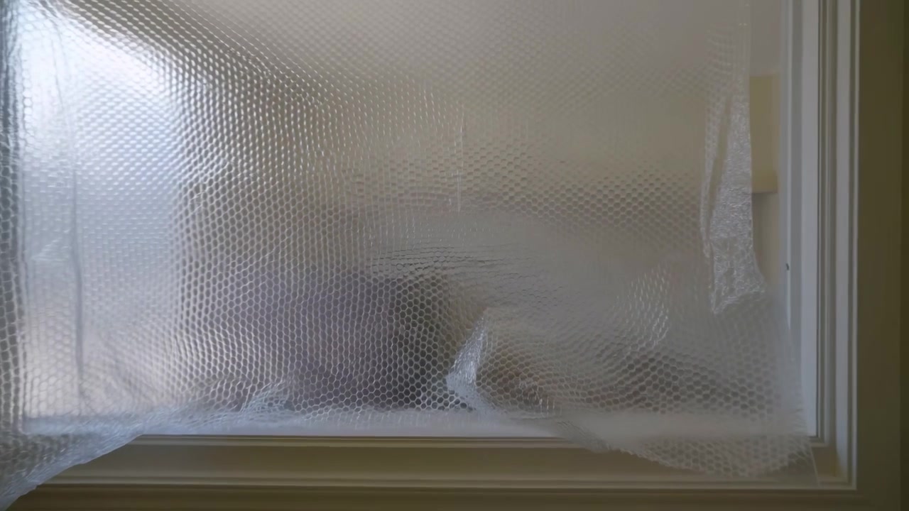 Translucent bubble wrap sheet stretched across window with shifting highlights, subtle pocket compression, repeating circular texture, reflective plastic surface, and soft studio light