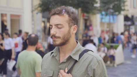 Young-man-with-eyes-closed-in-crowded-street.