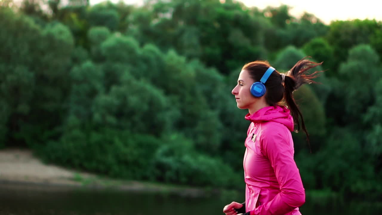 una carrera matutina en el parque cerca del estanque en los rayos soleados del amanecer, la niña se está preparando para mariano y llevar un estilo de vida saludable