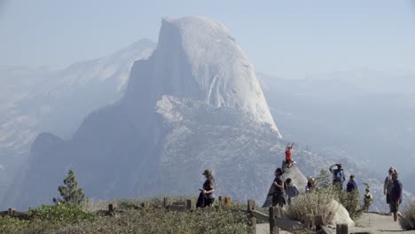 Un-Niño-Sobre-Una-Roca-En-Glacier-Point,-El-Parque-Nacional-De-Yosemite-Half-Dome-Y-Las-Montañas-De-Sierra-Nevada-En-La-Distancia