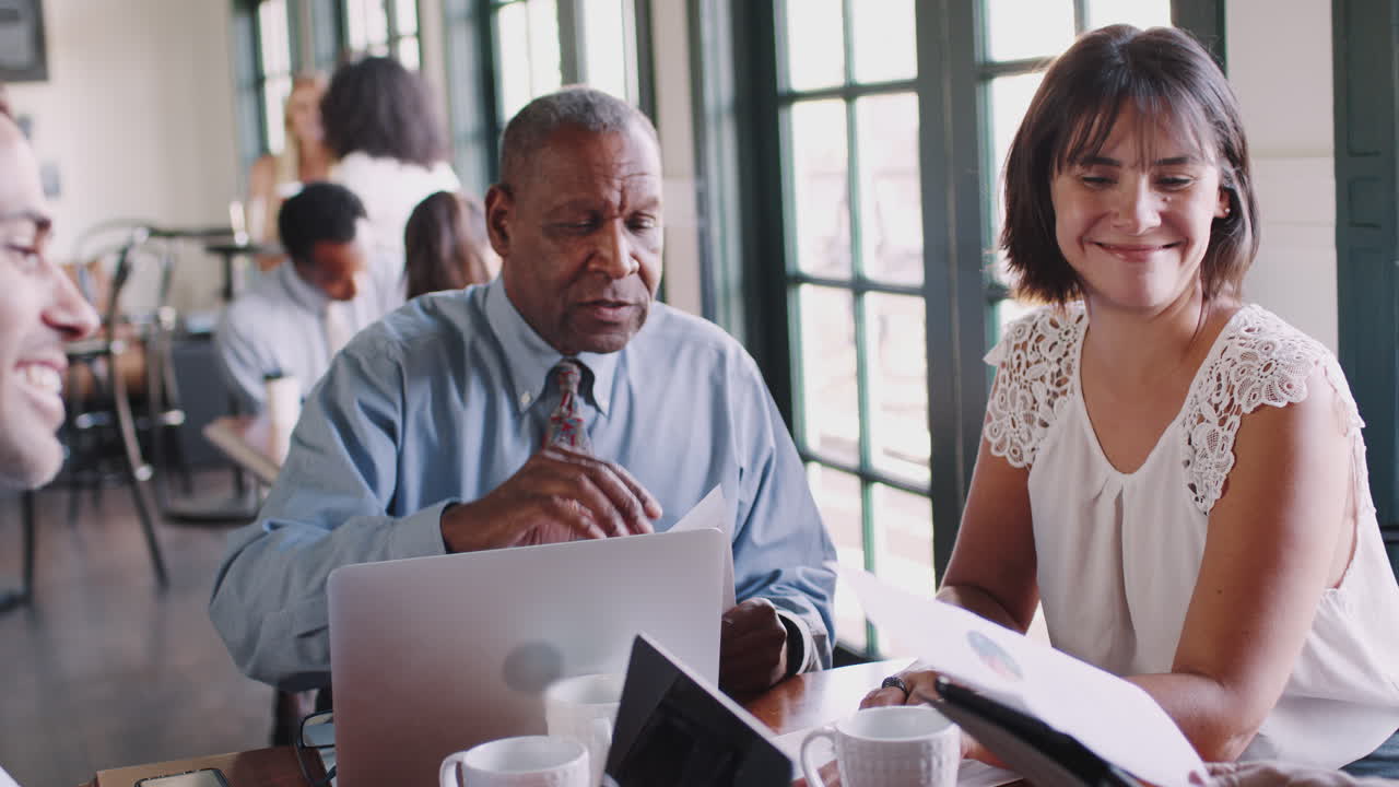 Business Team Having Informal Meeting Around Table In Coffee Shop