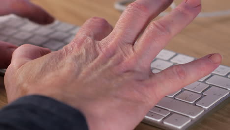Close-up-of-Man-hands-typing-with-two-fingers-on-white-small-keyboard-on-office-table