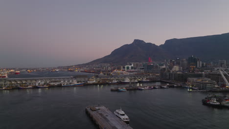 Slide-and-pan-shot-of-marina-at-dusk.-City-and-Table-Mountain-massif-against-twilight-sky-in-background.-Cape-Town,-South-Africa