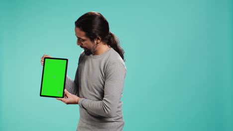hombre alegre presentando video en la tableta de pantalla verde