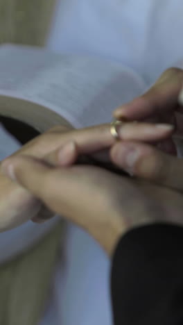 groom placing ring on brides finger in front of priest