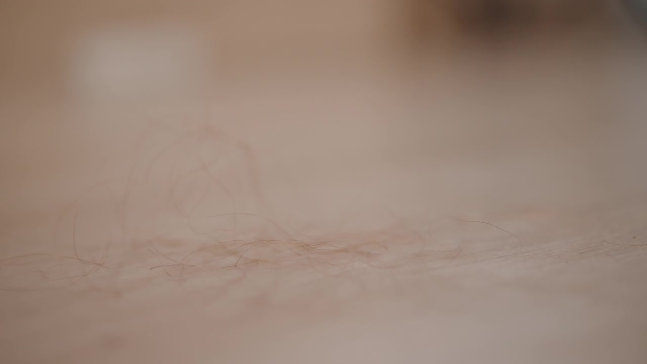 Sudut rendah, close-up lantai krem halus dengan cahaya hangat, kedalaman dangkal, dan blur lembut, menunjukkan butiran halus, pantulan samar, dan gerakan tenang di permukaan kosong yang bersih, dengan lantai, krem, blur
