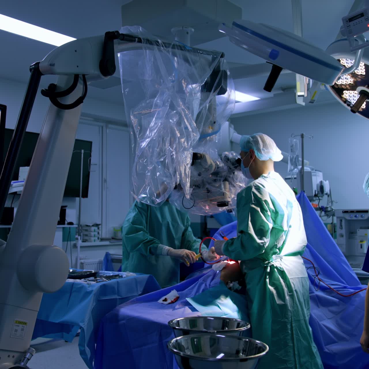 Doctor looks at the microscope applying tools and devices at operation. Assisting nurse uses syringe. Procedure is shown at the monitor