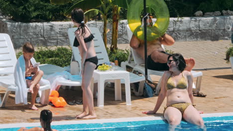 people sitting by the poolside of a resort swimming pool during summer holiday