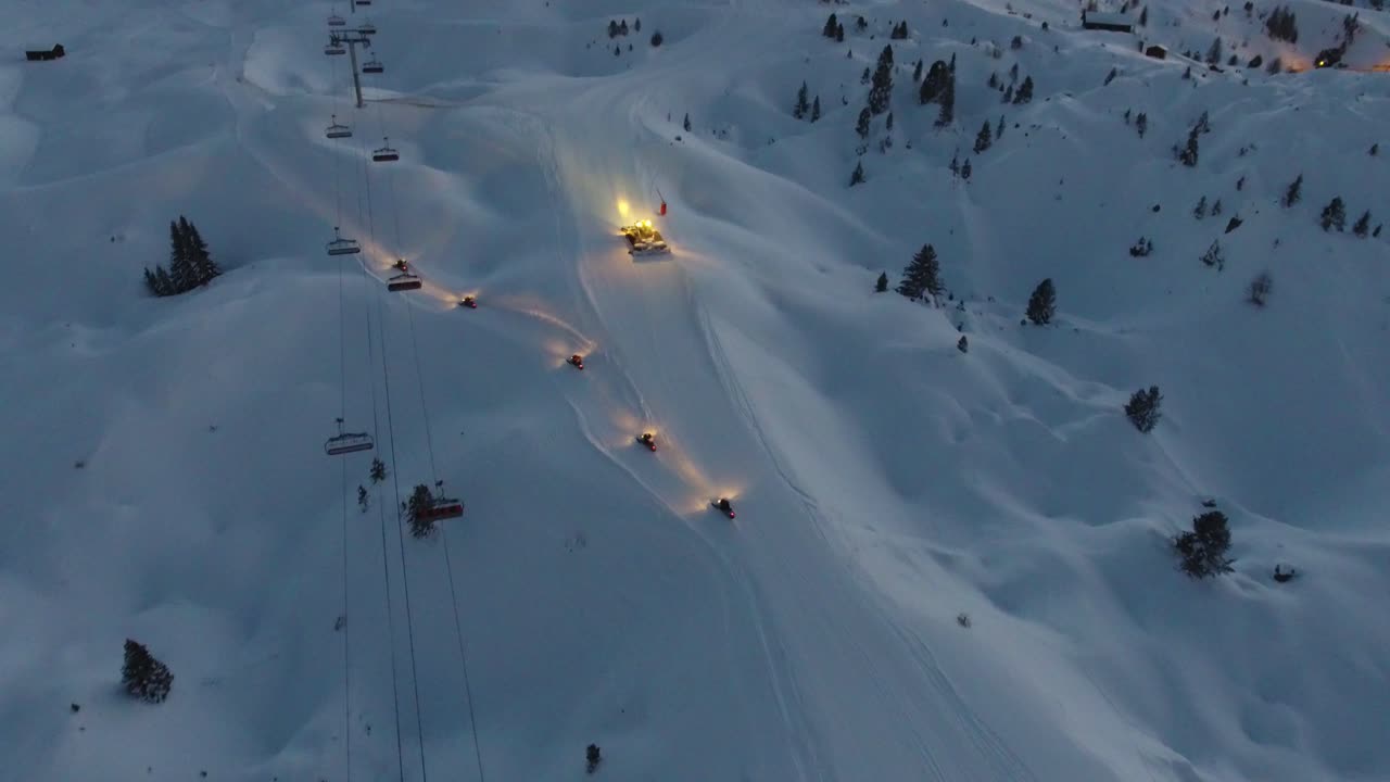 vista aérea de un limpiador de nieve y vehículos de nieve en una pista de esquí en los alpes franceses