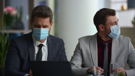 International-business-group-discuss-marketing-wear-face-mask-in-diverse-office.