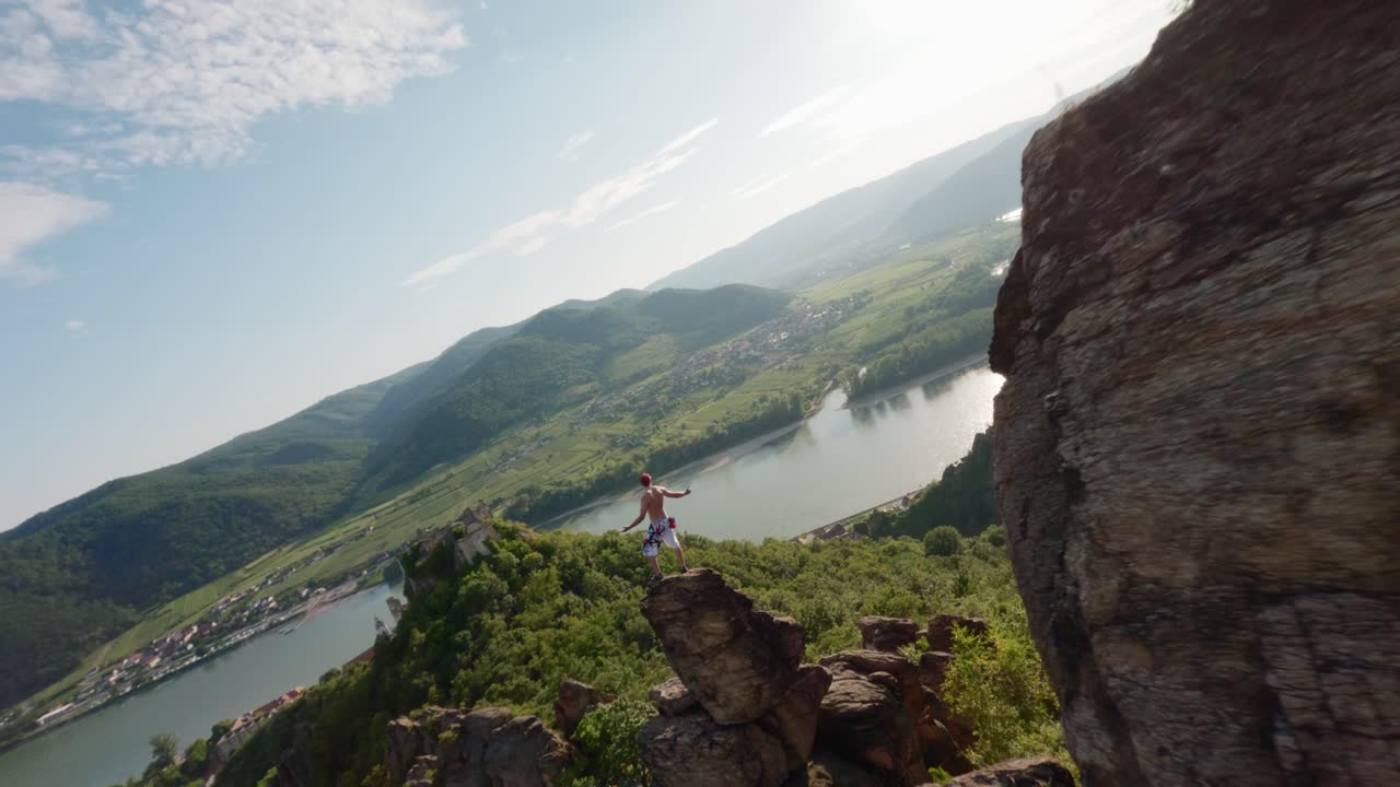 hombre en la cima de la cresta de la montaña, avión no tripulado rápido fpv, disparo aéreo con velocidad, rey del mundo pose, escalador de montaña, persona en la cima de la colina, valle del río danubio panorama general, volando alrededor, volando rápido