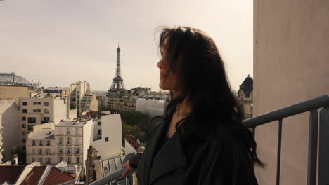 encantadora turista morena en el balcón con vistas a la ciudad en el fondo en parís, francia