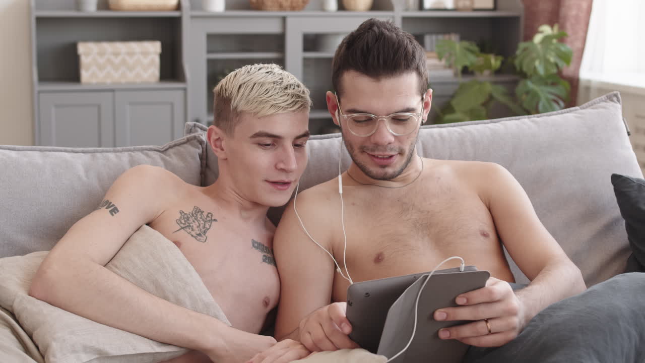 Couple Sitting on Sofa and Using Digital Tablet